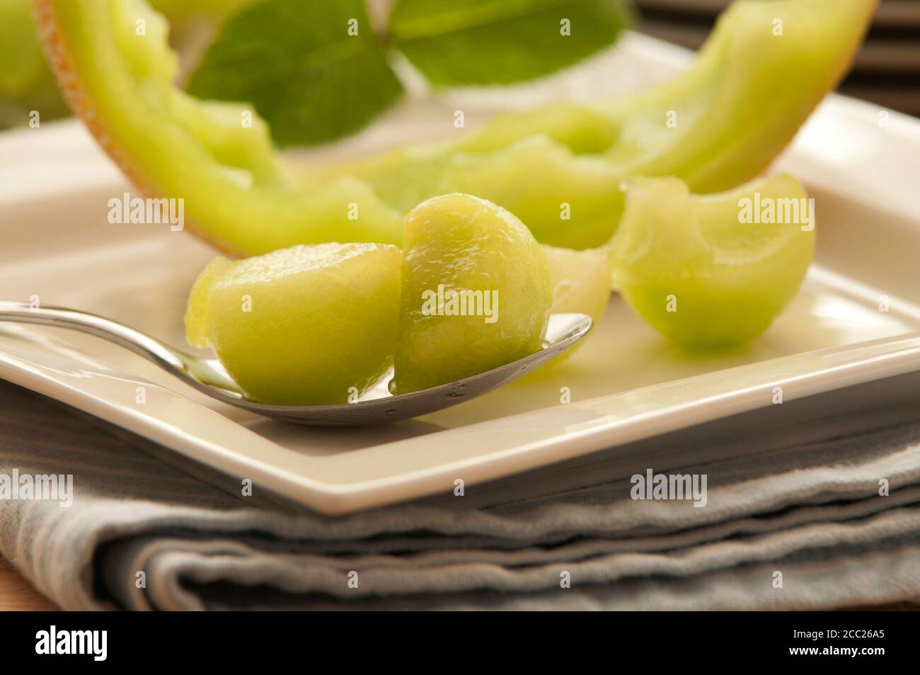 Piastra di melone Honeydew con cucchiaio sul tovagliolo, close up Foto Stock