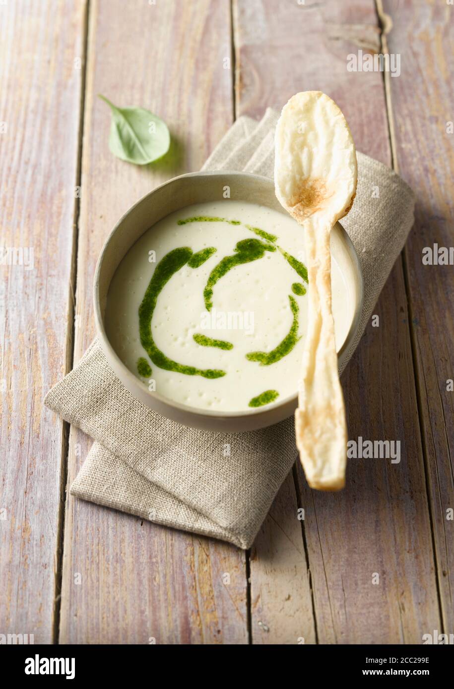 Ciotola di zuppa di patate con pesto e pasta sfoglia cucchiaio sul tavolo di legno, close up Foto Stock