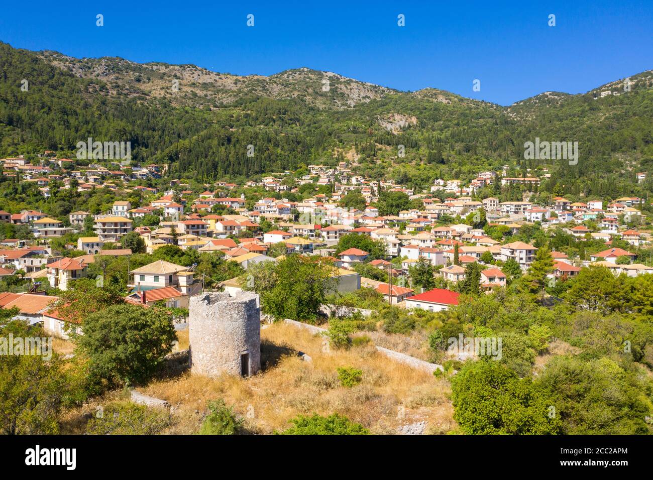 Un mulino a vento in rovina con edifici dietro a Karya, un tradizionale villaggio di montagna a Lefkada, Isole IONIE, Grecia Foto Stock