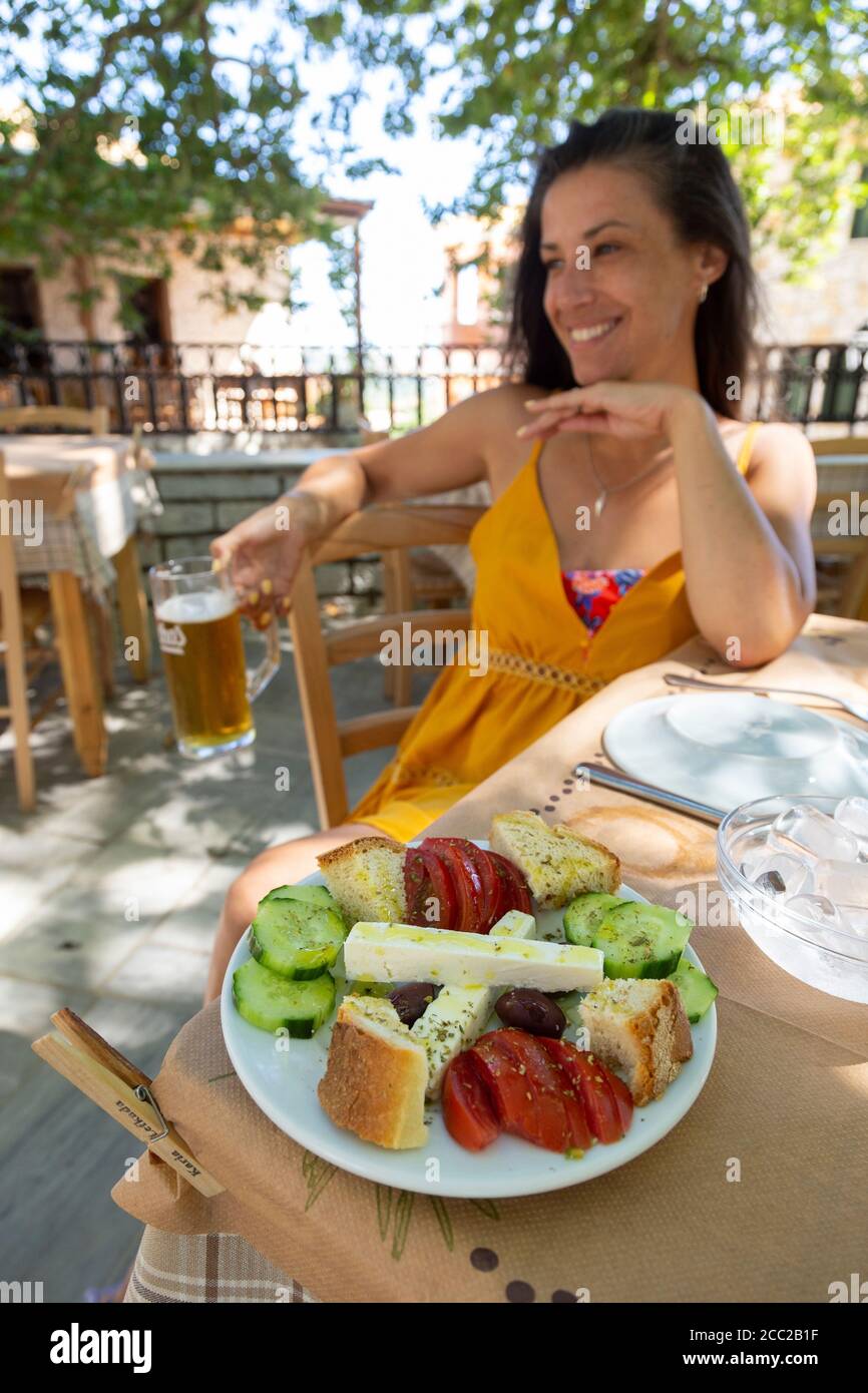 Una ragazza seduta in una taverna con un antipasto e una pinta di birra a Karya, Lefkada, Isole IONIE, Grecia Foto Stock
