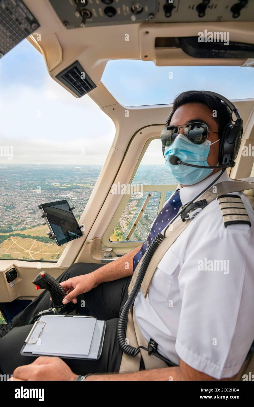 Ritratto verticale di un pilota che indossa una maschera che vola in elicottero sopra Londra sud-orientale. Foto Stock