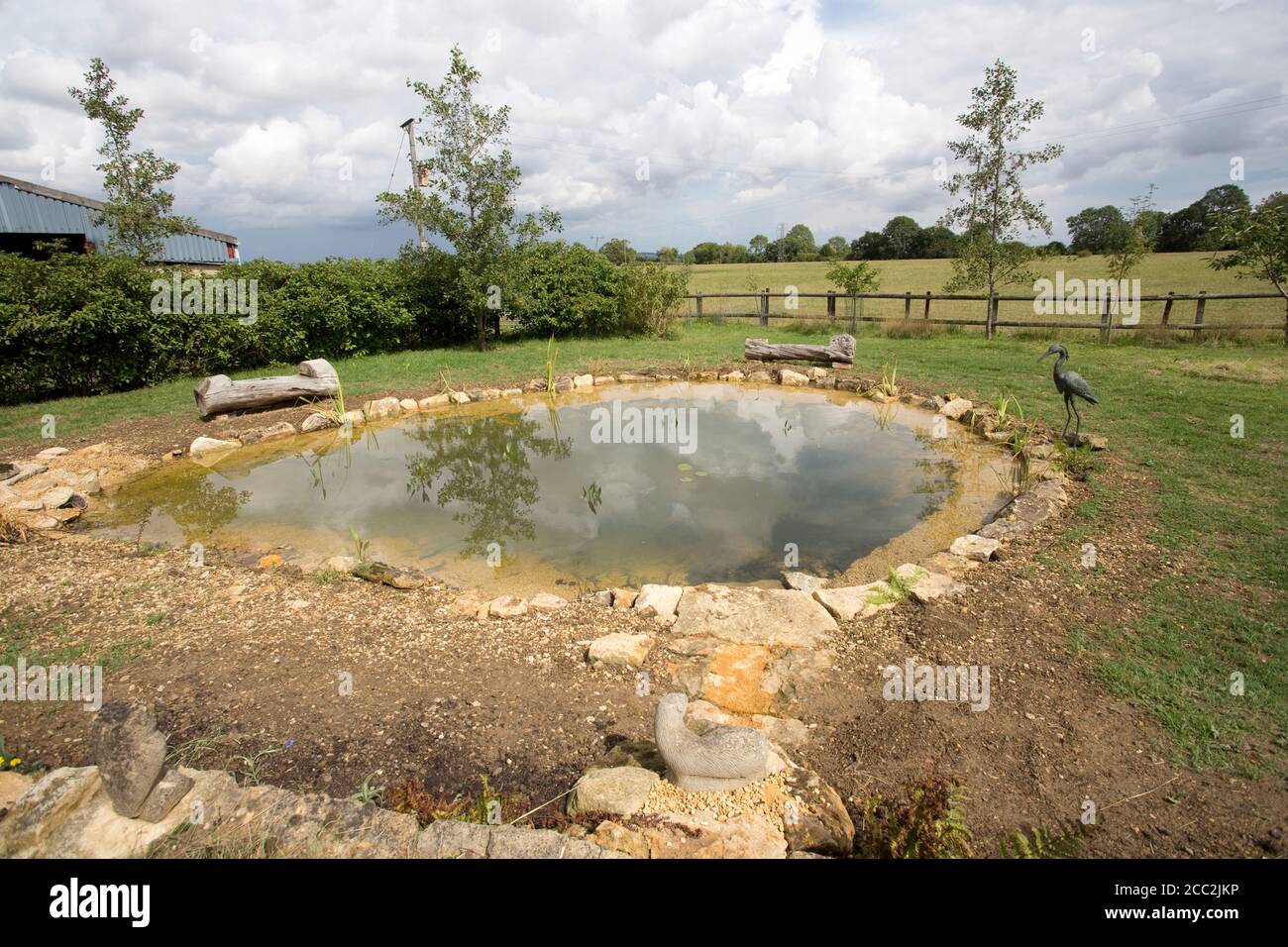 Recentemente completato grande laghetto giardino con primo impianto di piante laghetto e circondato da pietre Cotswold, Colemans Hill Farm, Mickleton, Regno Unito Foto Stock