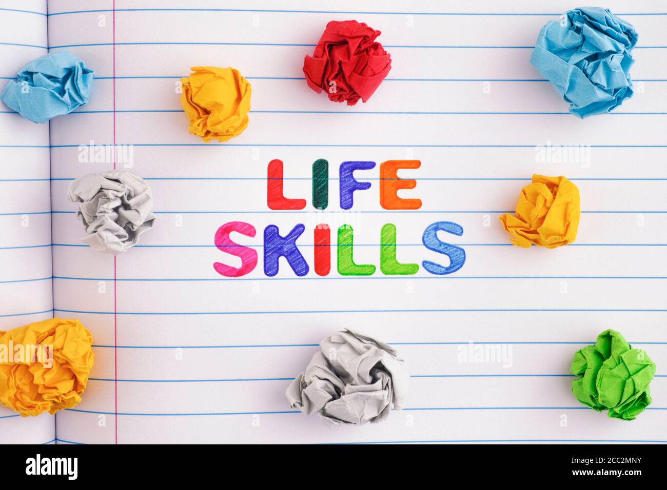 Abilità di vita. Le parole Life Skills su un foglio di notebook con alcune palline colorate di carta sminuzzata intorno a loro. Primo piano. Foto Stock