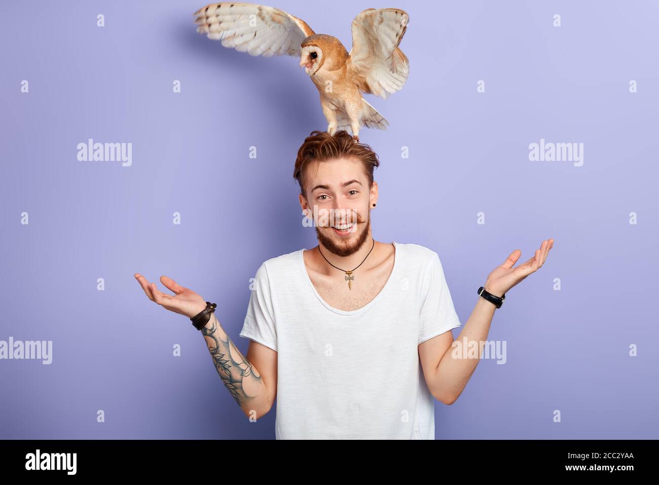 divertente giovane uomo con un uccello sulla sua testa spallucce, isolato sfondo blu, studio shot. stile di vita, tempo libero, tempo spring Foto Stock