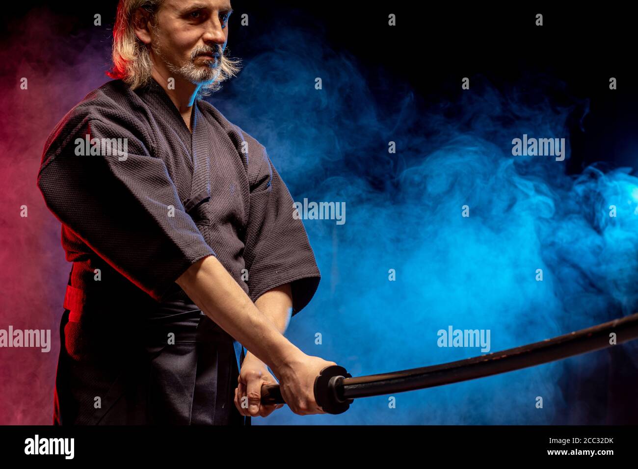 Combattente caucasico maschile kendo in stile tradizionale giapponese di abbigliamento, armatura protettiva, utilizzando shinai. Pratica lotta isolato sopra camera fumosa Foto Stock