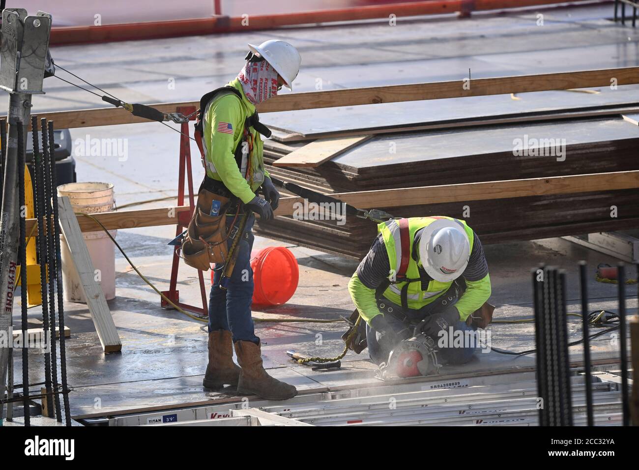 I lavoratori edili che indossano attrezzature di sicurezza e rivestimenti per il viso si trovano sul posto di lavoro del parcheggio nel quartiere di Rainey Street, vicino al centro di Austin, Texas. Foto Stock