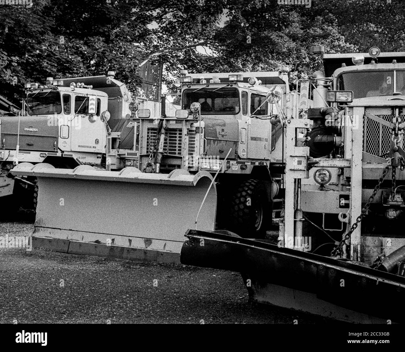 Gli spazzaneve classici sono pronti per l'inverno mentre sono parcheggiati in un vicolo fuori stagione. L'immagine è stata acquisita con una pellicola analogica in bianco e nero. Foto Stock