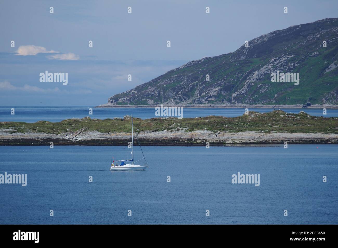 Un piccolo yacht in motorizzazione nel Sound of Jura, Scozia occidentale, al porto di Melfort in una giornata estiva limpida che mostra il mare blu, il cielo e l'isola oltre Foto Stock