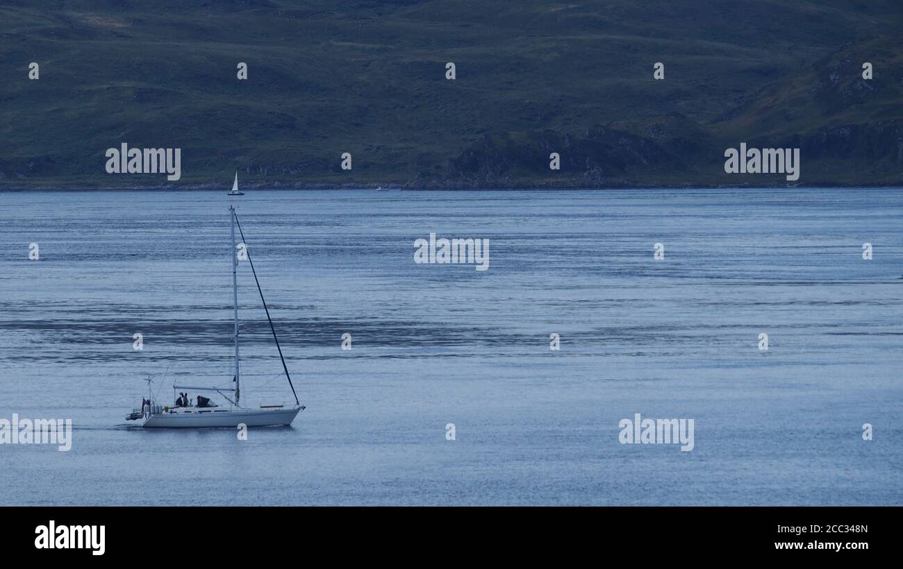 Un piccolo yacht in motorizzazione nel Sound of Jura, Scozia occidentale, al porto di Melfort in una giornata estiva limpida che mostra il mare blu, il cielo e l'isola oltre Foto Stock