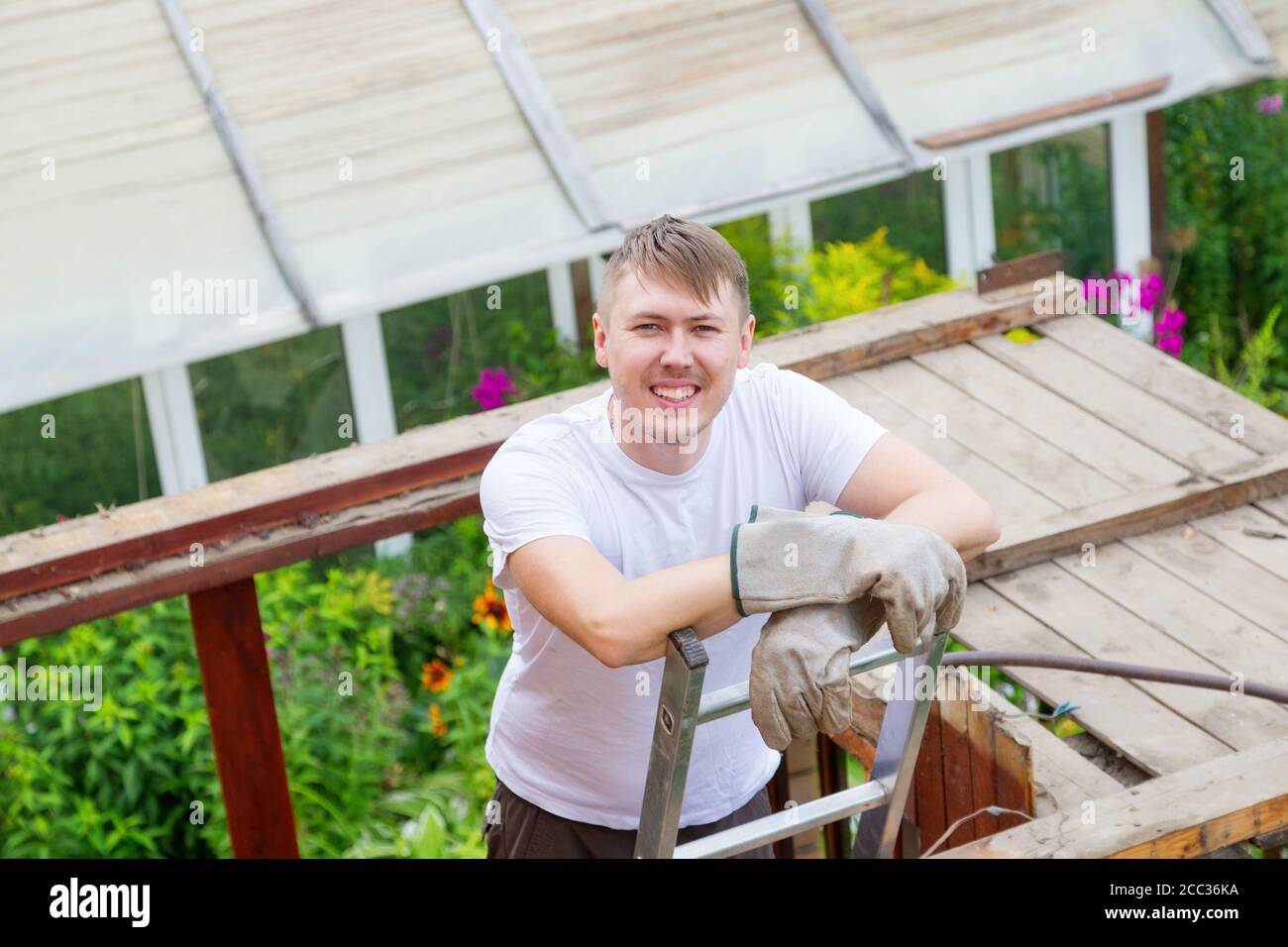 Un uomo si alza sulle scale, riposandosi e sorridendo alla telecamera Foto Stock