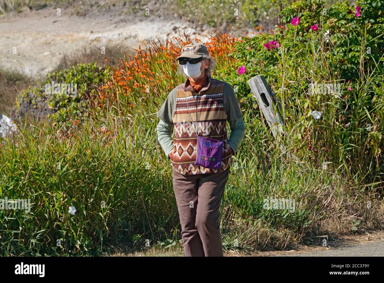 Una donna che indossa una faccia che copre passeggiate lungo un percorso sulla costa dell'Oceano Pacifico vicino alla città di Yachats, Oregon. Foto Stock