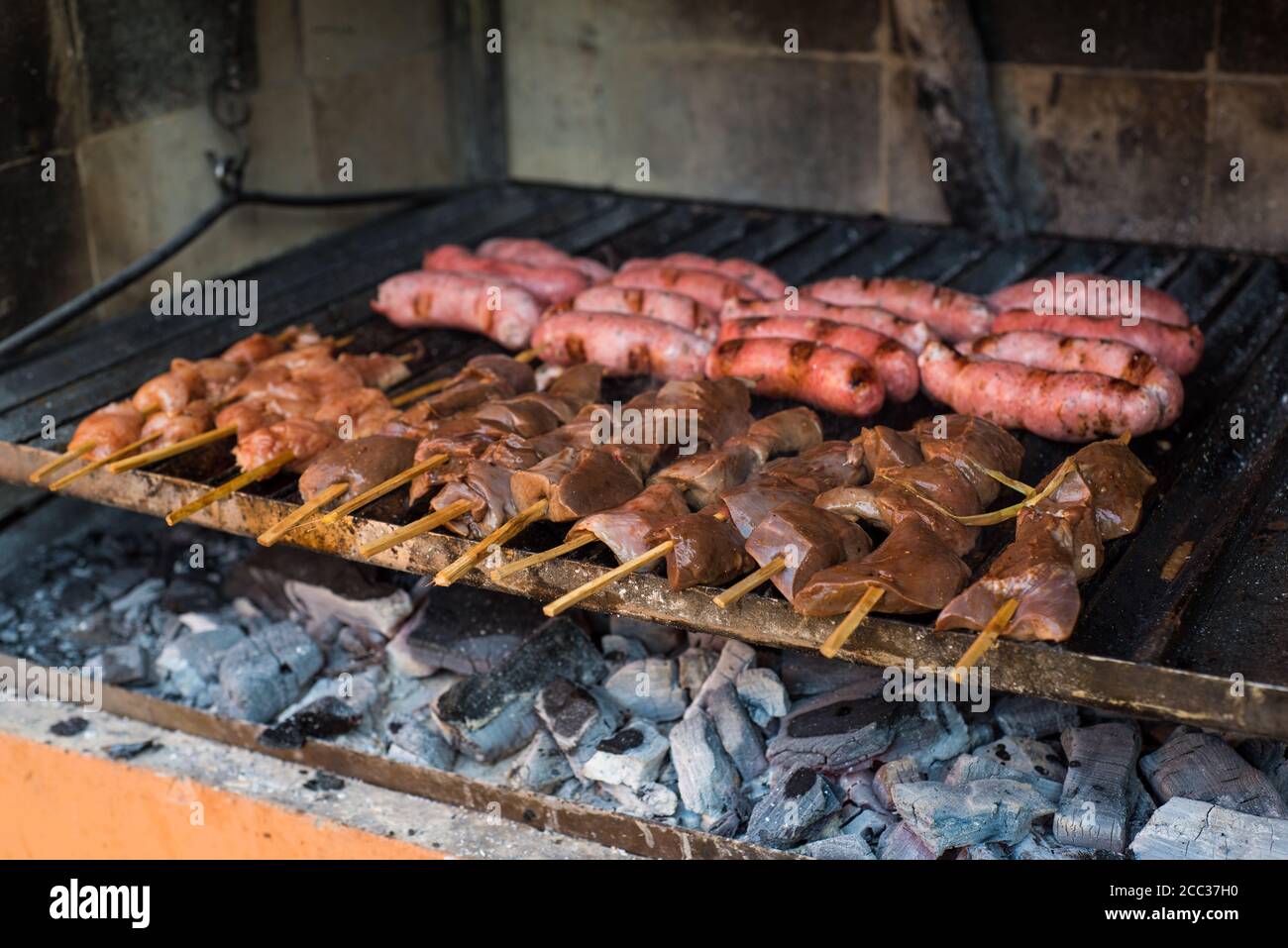 Parrillada peruviana tradizionale. Carni crude in barbecue rustico. Cuore crudo di manzo spiedato (anticuchos), pollo spiedato e salsicce di maiale. Foto Stock