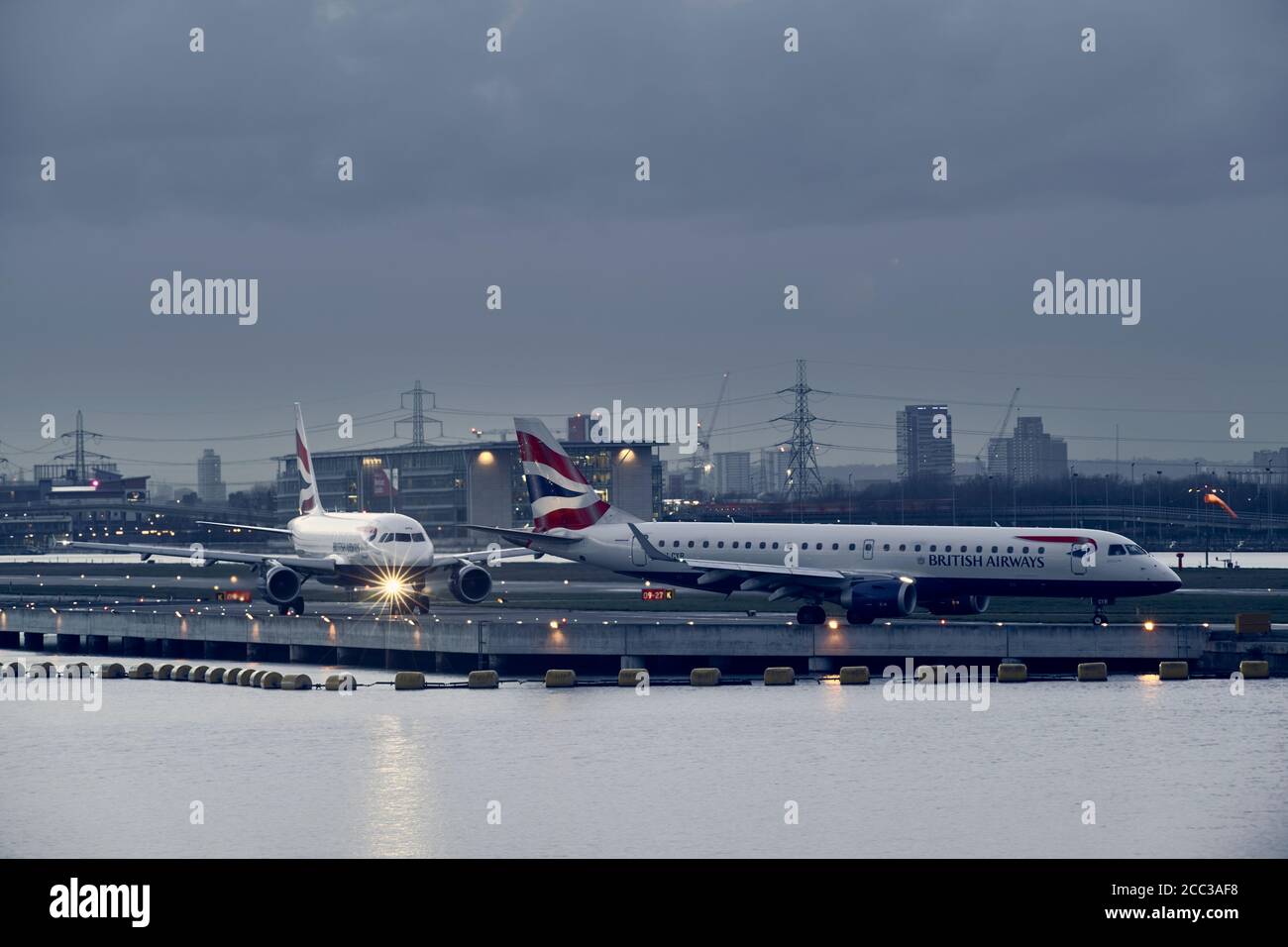 Gli aerei della British Airways tassano sulla pista di London City Aeroporto Foto Stock