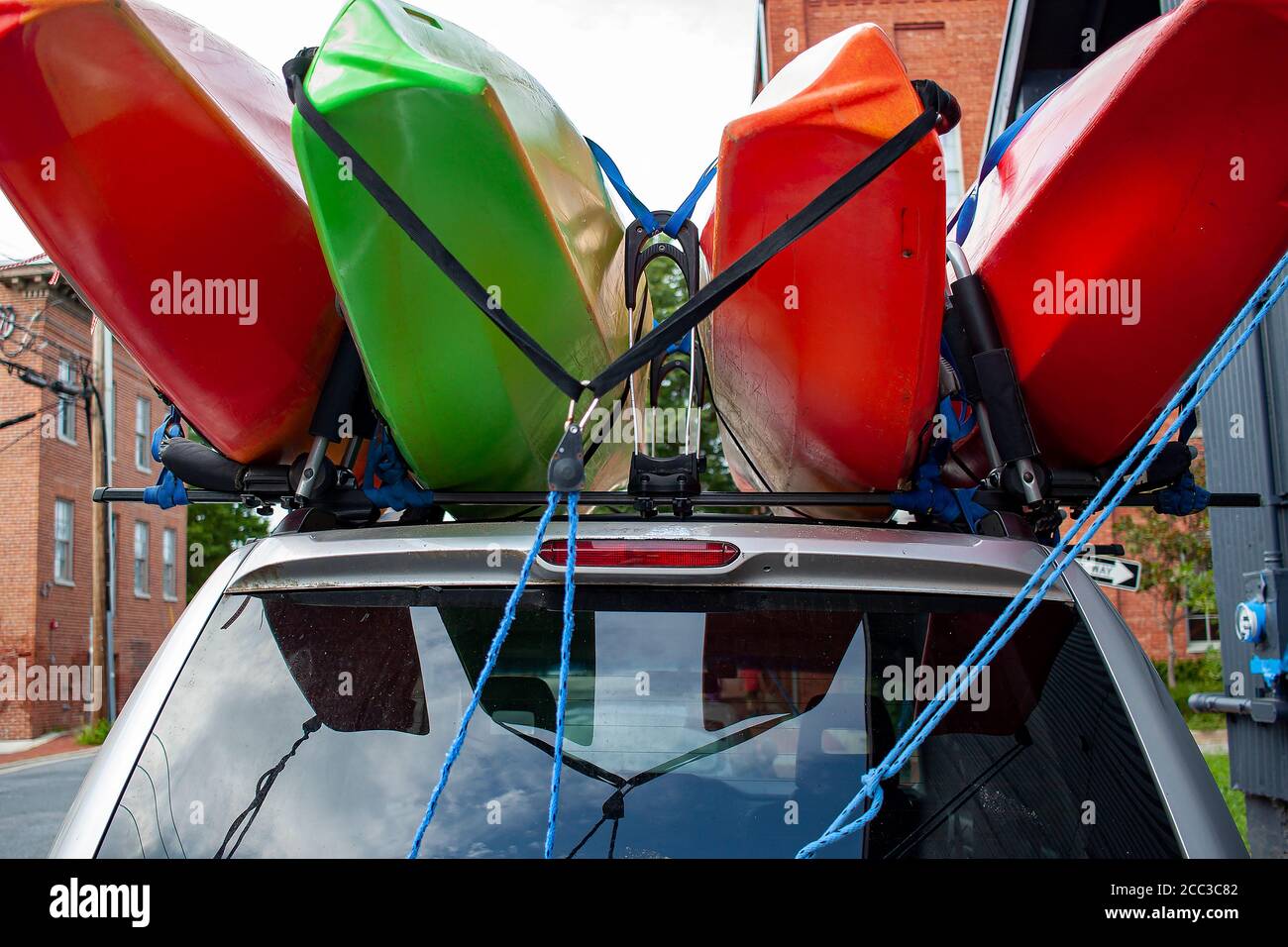 Primo piano, profondità di campo poco profonda, immagine di vista  dell'occhio di bug di quattro kayak di dimensioni complete di colore rosso  e verde caricati sulla parte superiore di un'auto SUV utilizzando