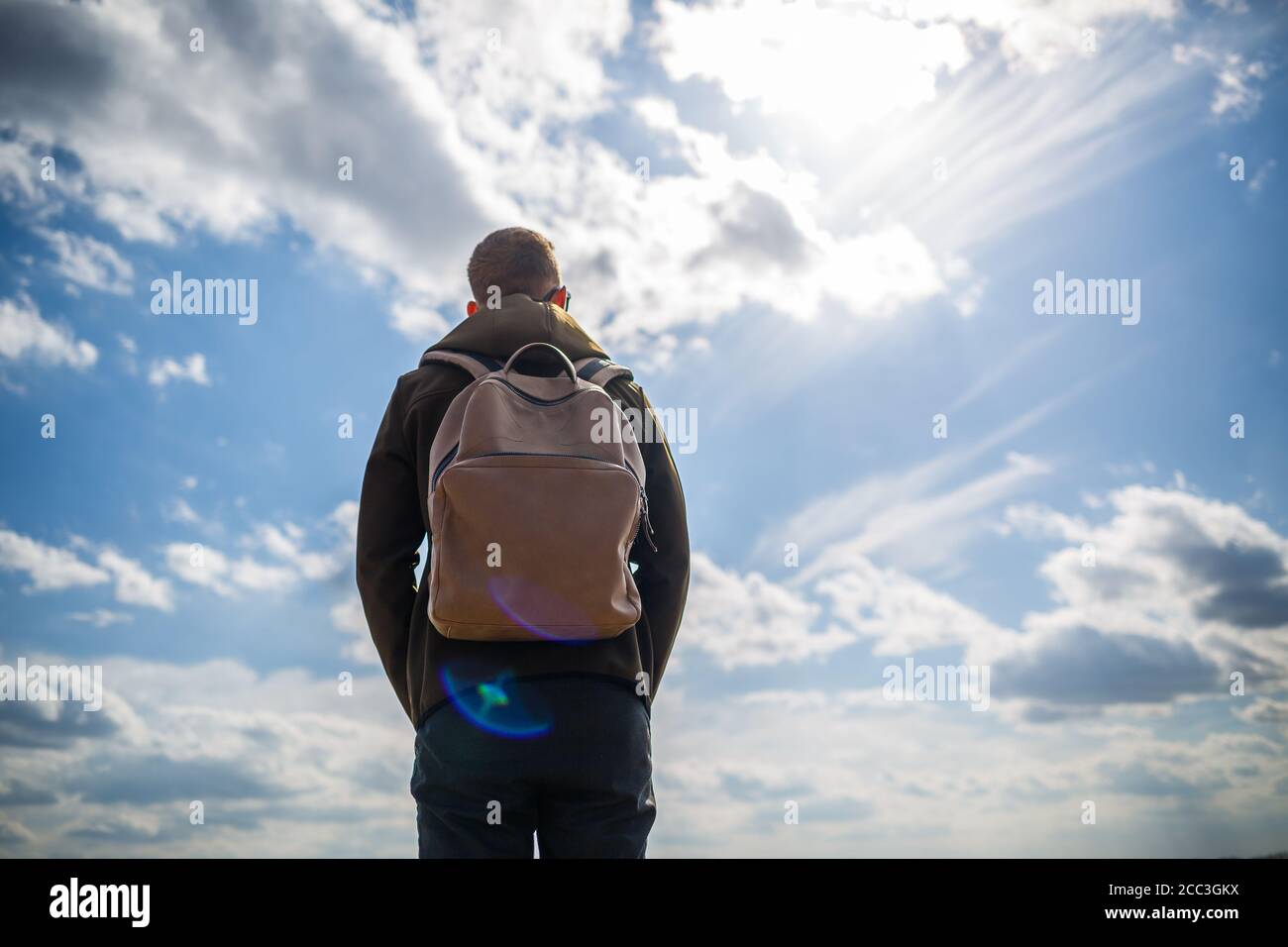 ragazzo turista freelance con uno zaino sulle spalle contro un cielo blu  con nuvole bianche, giorno di sole luminoso Foto stock - Alamy