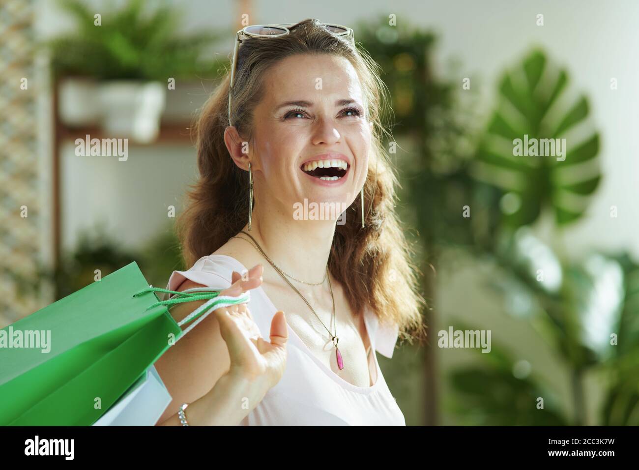 donna sorridente alla moda shopper in blusa rosa con borse di carta per lo shopping. Foto Stock