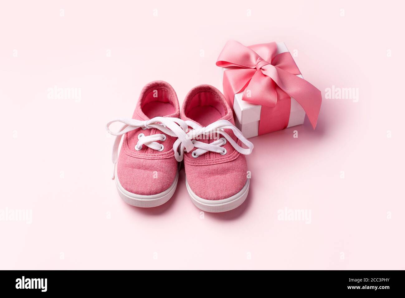 Scarpe rosa per bambini e confezione regalo, concetto di primi passi, compleanno, acquazzone per bambini, attesa, gravidanza, maternità, maternità, genitorialità. Monoch Foto Stock