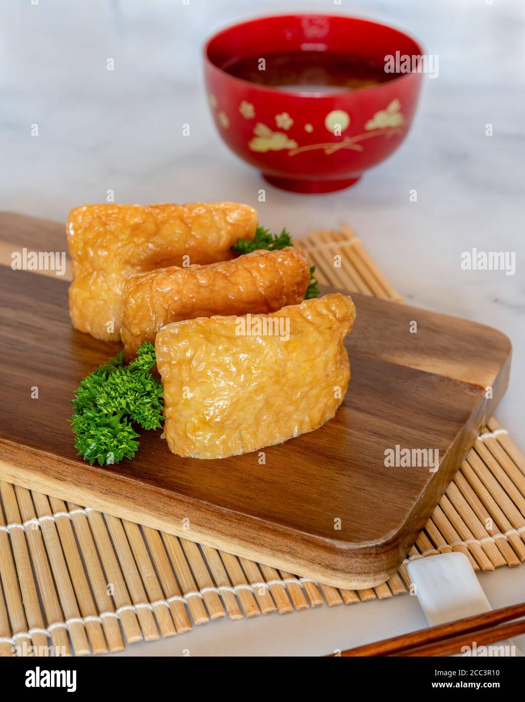 Inarisushi su una tavola di legno con sfondo di zuppa di miso sfocato Foto Stock