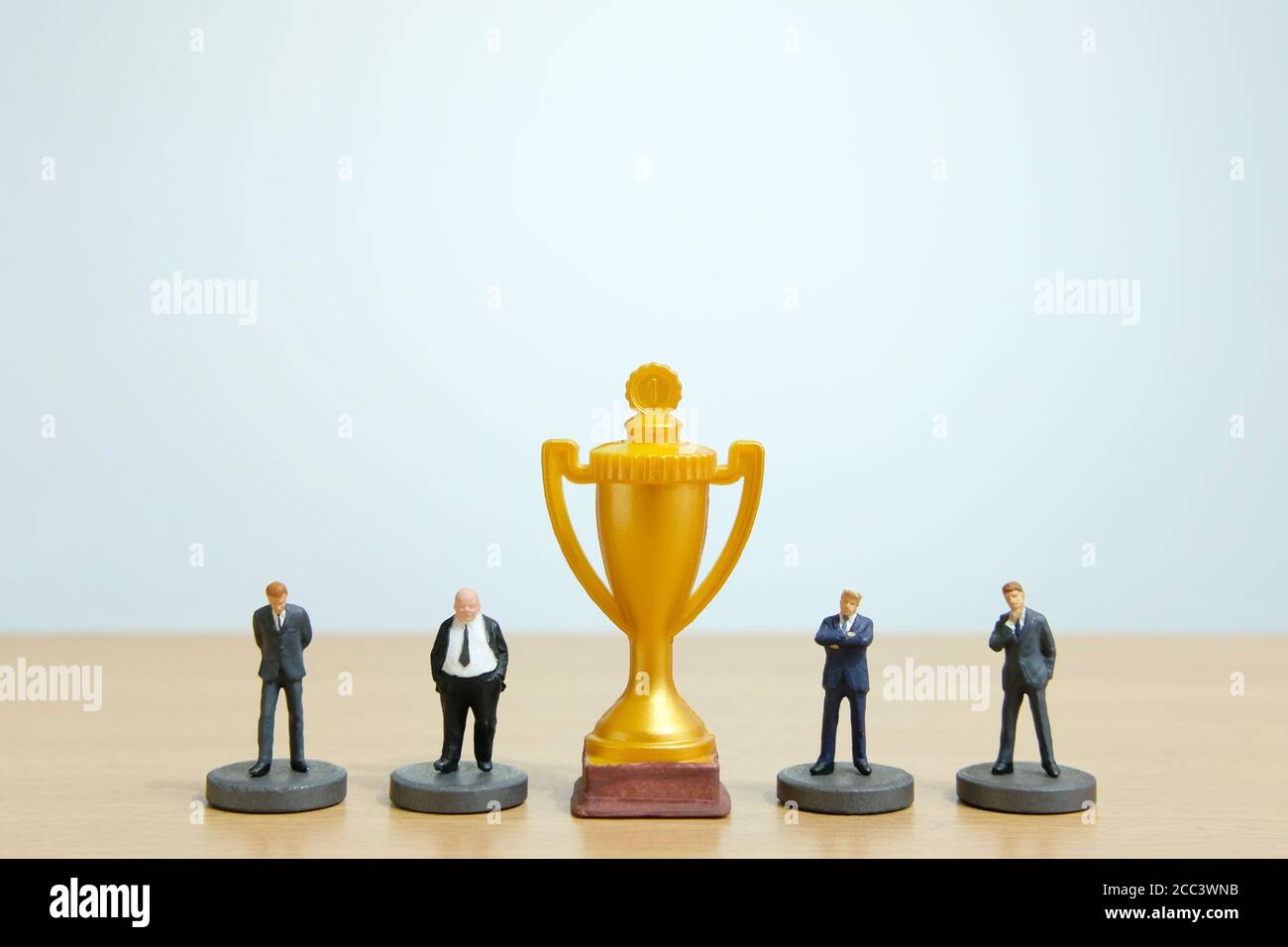Concetto di business in miniatura - riga di business uomo d'affari con trofeo d'oro al centro Foto Stock
