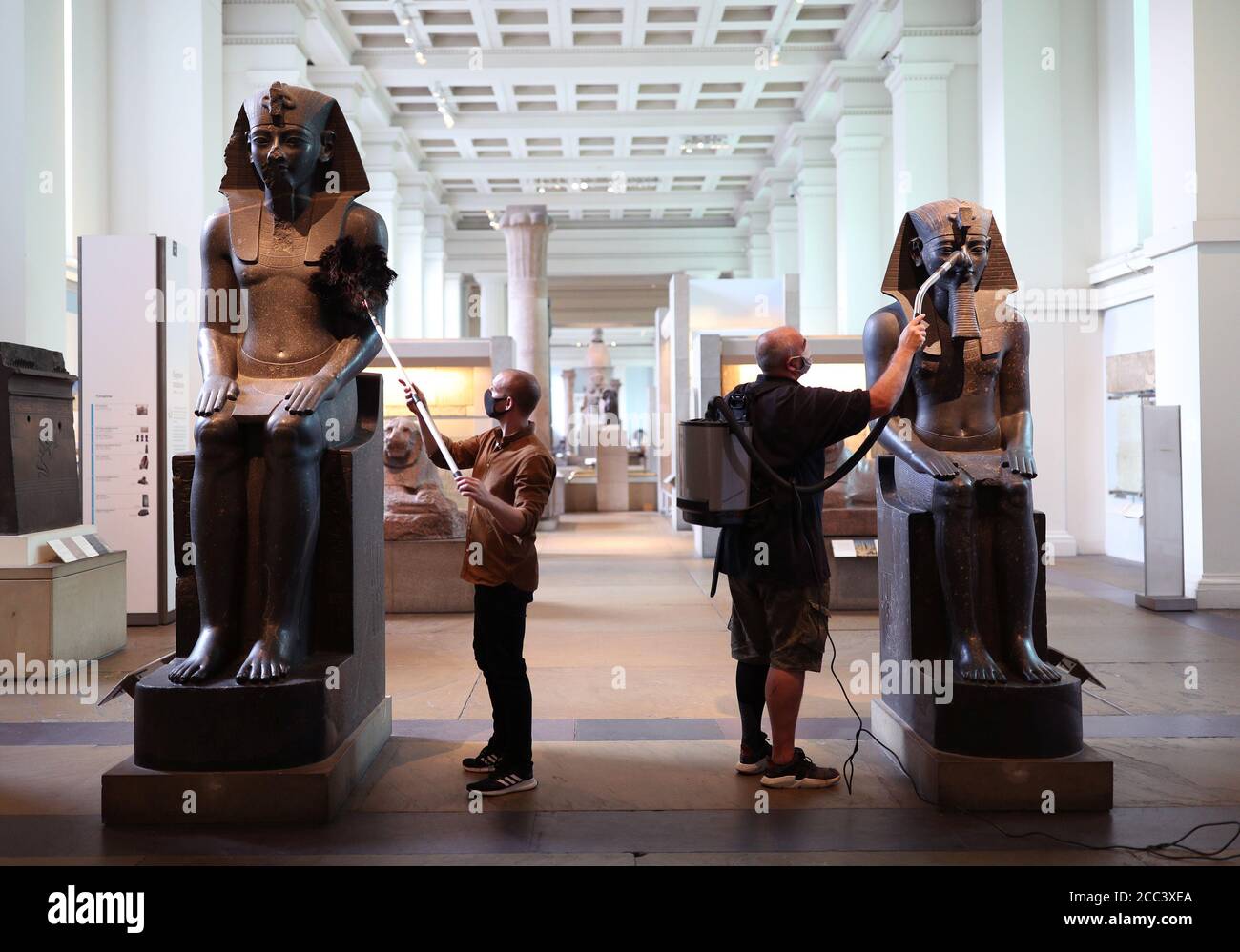 I manager della collezione Alex Truscott (a sinistra) e Evan York spolverano le statue di Amenhotep III (circa 1390-1352 a.C.), nella Egyptian Sculpture Gallery al British Museum di Londra, mentre si preparano a riaprire al pubblico il 27 agosto dopo il blocco del coronavirus. Prima della riapertura, il British Museum ha avviato il più grande programma di pulizia individuale degli ultimi decenni. Foto Stock