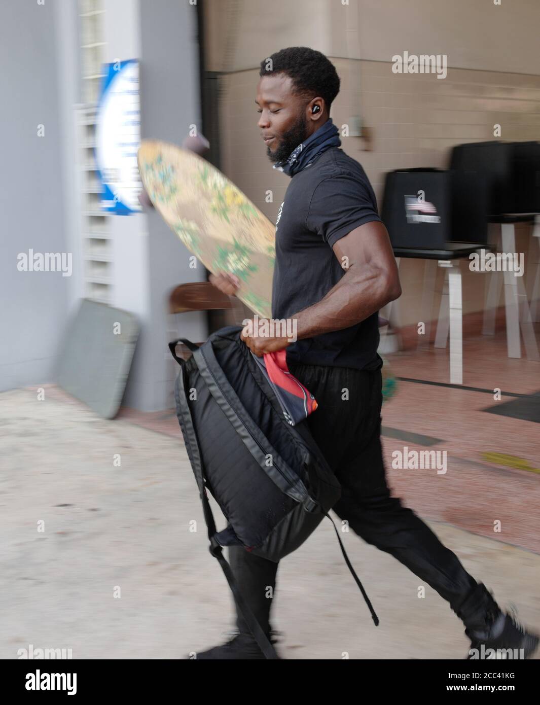 Miami, Stati Uniti. 18 agosto 2020. Il residente della Florida di Miami porta il suo skate board e zaino dopo che ha lanciato il suo scrutinio il giorno delle elezioni primarie per i candidati alla stazione 2 di Miami Fire and Rescue a Miami, Florida il martedì 18 agosto 2020. Le linee dei siti di polling sono più brevi e in alcuni casi inesistenti a causa del COVID-19, Coronavirus Pandemic. Foto di Gary i Rothstein/UPI Credit: UPI/Alamy Live News Foto Stock