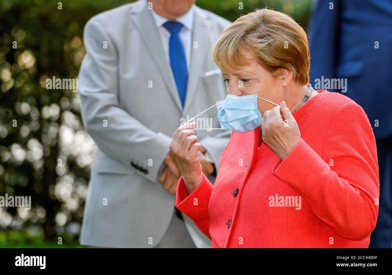 18 agosto 2020, Renania Settentrionale-Vestfalia, Duesseldorf: Durante la sua visita in Renania Settentrionale-Vestfalia, la Cancelliera Angela Merkel (CDU) toglie la sua bocca e il naso nel parco della Ständehaus prima di una sessione fotografica con il gabinetto. La Merkel partecipa ad una riunione del governo della Renania Settentrionale-Vestfalia e visita la miniera di carbone Zollverein. Foto: Sascha Schuermann/AFP Pool/dpa Foto Stock