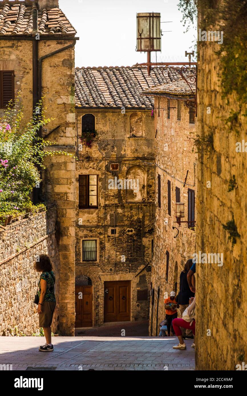 Vista pittoresca di una strada inclinata che conduce ad una tipica casa medievale nella famosa cittadina collinare di San Gimignano, Toscana, Italia. Foto Stock