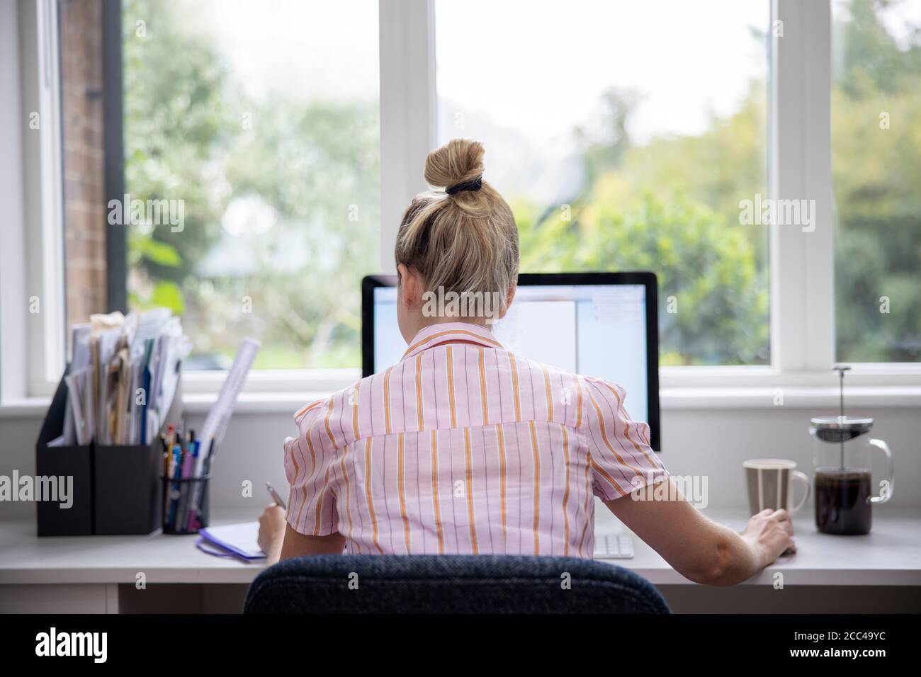 Vista posteriore di Donna che lavora da casa su computer in Ufficio domestico Foto Stock