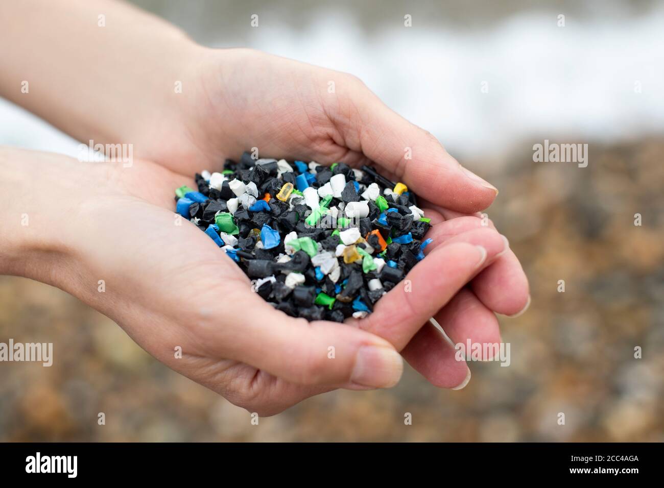 Primo piano di Hand Holding Plastic granulato inquinante Beach Foto Stock
