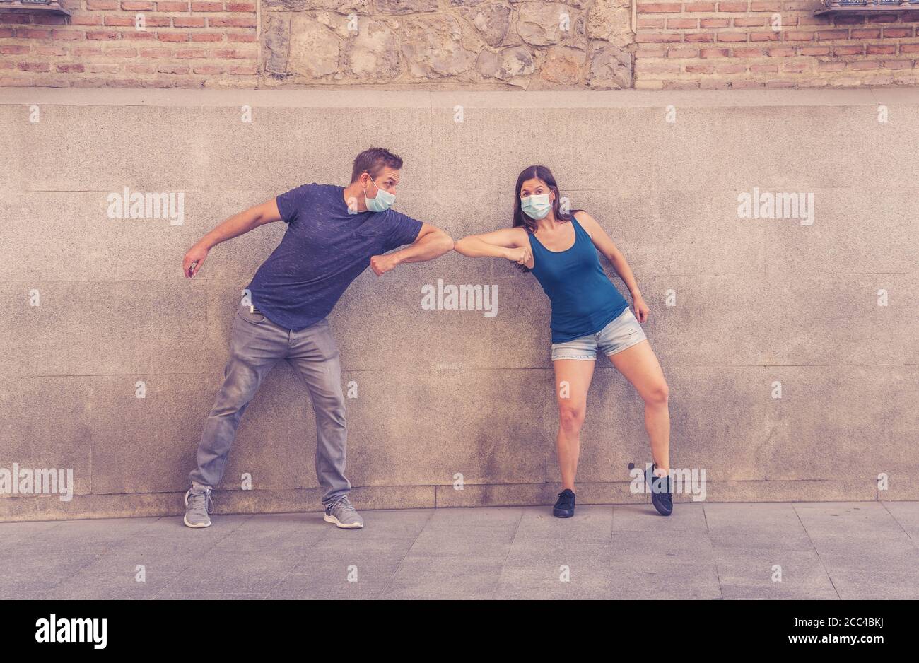 Il nuovo stile normale e di saluto. L'uomo e la donna scuotono i gomiti o i piedi mantenendo la distanza sociale per evitare che Coronavirus si diffonda. COVID-19 focolaio e d Foto Stock