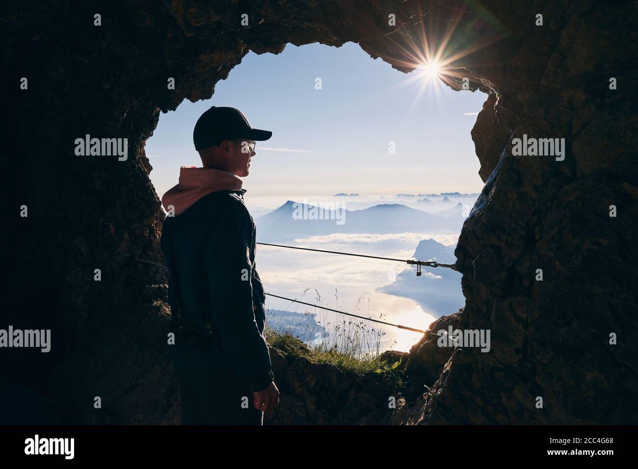 Uomo all'interno della grotta del Monte Pilatus guardando il paesaggio meraviglioso delle Alpi svizzere. Lucerna, Svizzera. Foto Stock