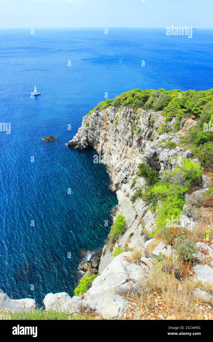 Nave a vela vicino scogliere rocciose con pineta, mare Adriatico, Croazia Foto Stock