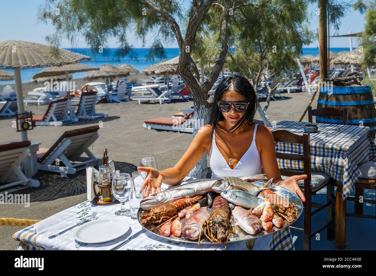 Bella, giovane donna sceglie il pesce fresco in un ristorante sulla spiaggia per grigliare. Foto Stock