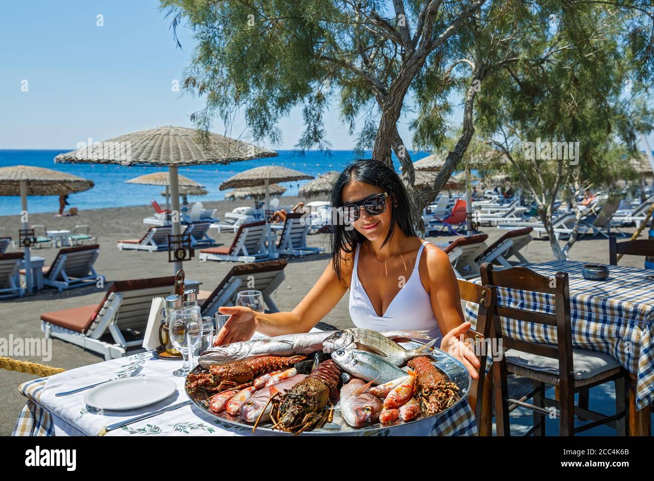 Bella, giovane donna sceglie il pesce fresco in un ristorante sulla spiaggia per grigliare. Foto Stock