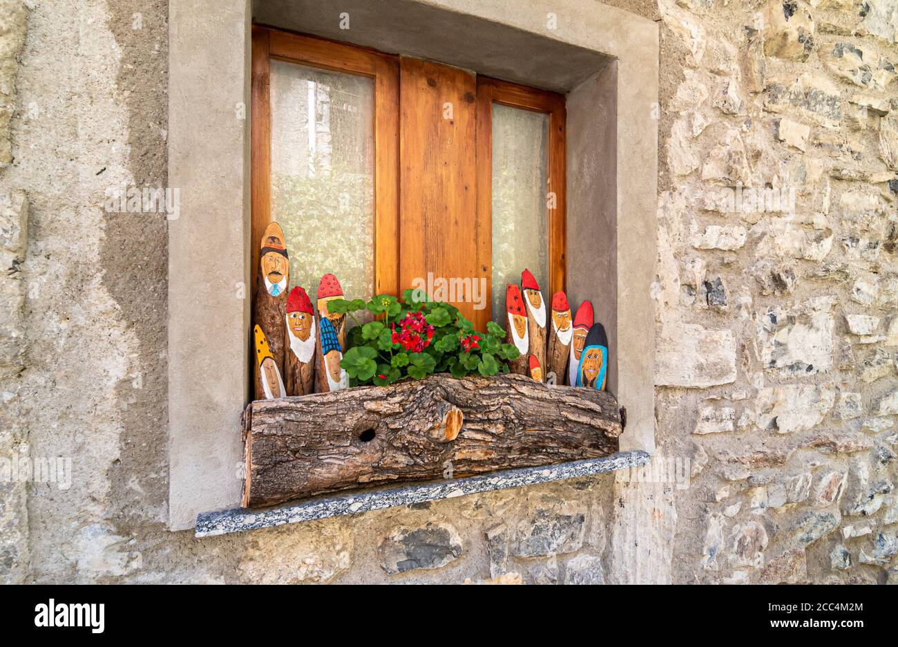 Vecchia finestra con colorate decorazioni in legno in una vecchia casa in pietra. Foto Stock