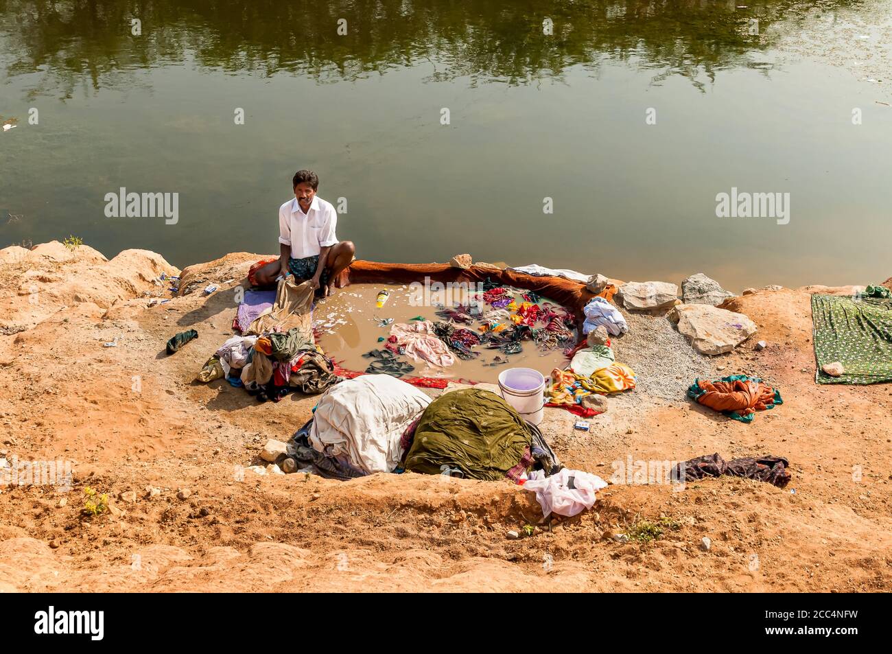 Puttaarthi, Andhra Pradesh, India - 11 gennaio 2013: Un uomo lavando abiti sulle rive del fiume nel villaggio di Puttaarthi, India Foto Stock