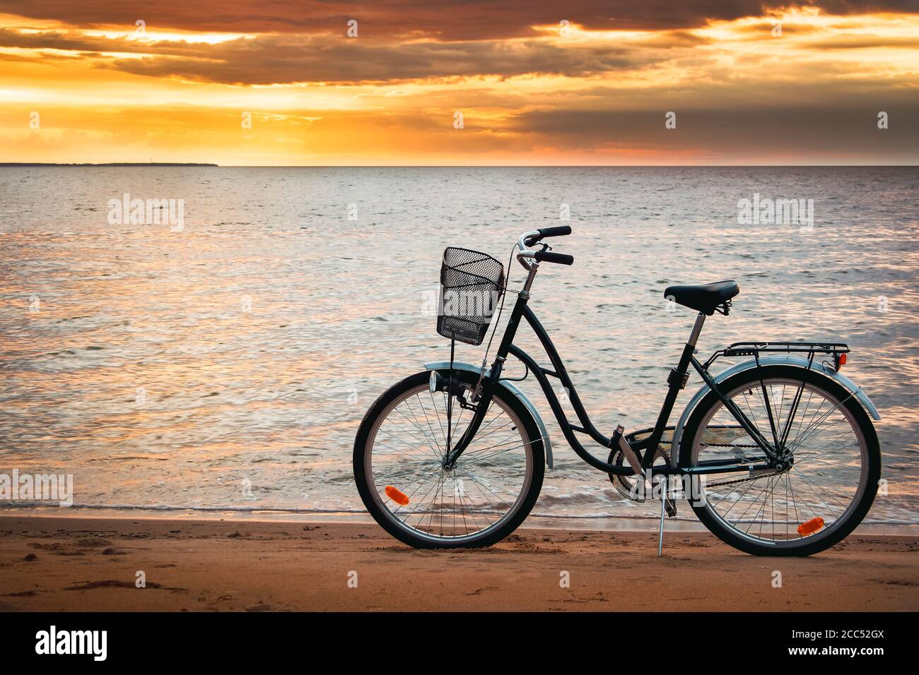 Solitaria in bicicletta al tramonto sul mare Foto Stock