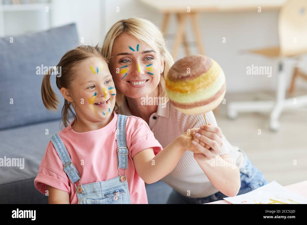 Madre sorridente che mostra la figlia con la sindrome di Down il modello del pianeta Foto Stock