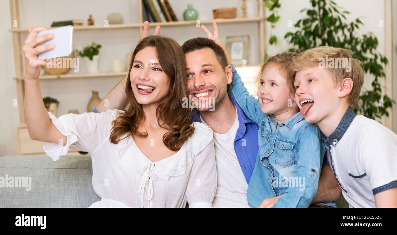 Divertente Famiglia divertirsi facendo Selfie in posa mostrando lingue indoor Foto Stock