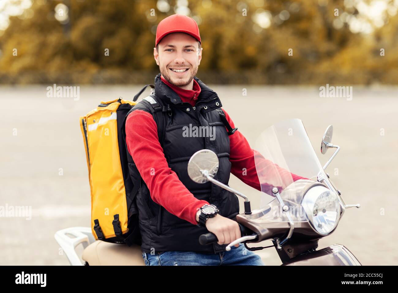 Happy Delivery Man con zaino giallo Riding Moto Scooter all'aperto Foto  stock - Alamy