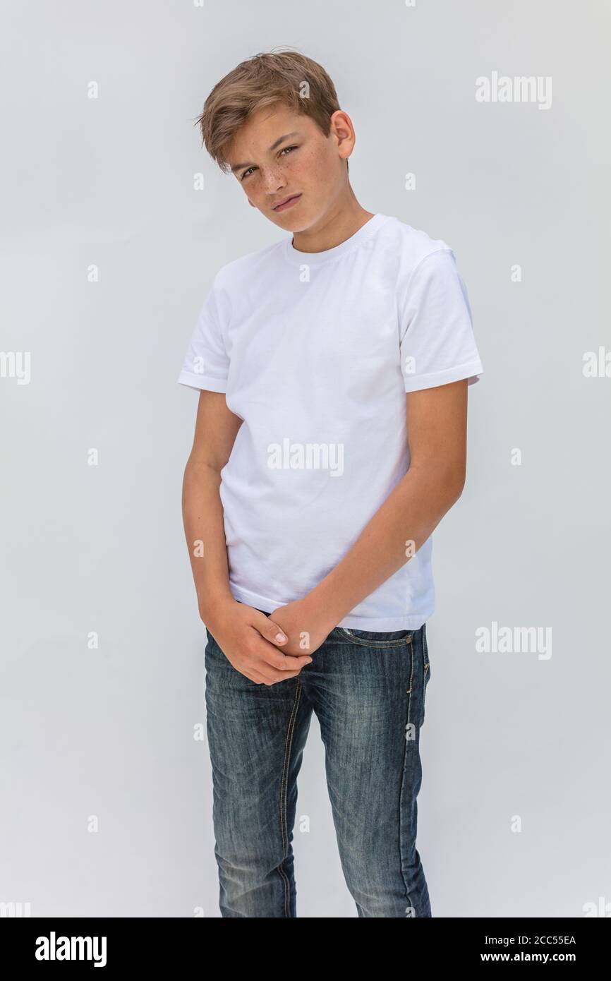 Ritratto in studio su sfondo bianco di un ragazzo adolescente maschio che indossa una t-shirt bianca e jeans blu Foto Stock