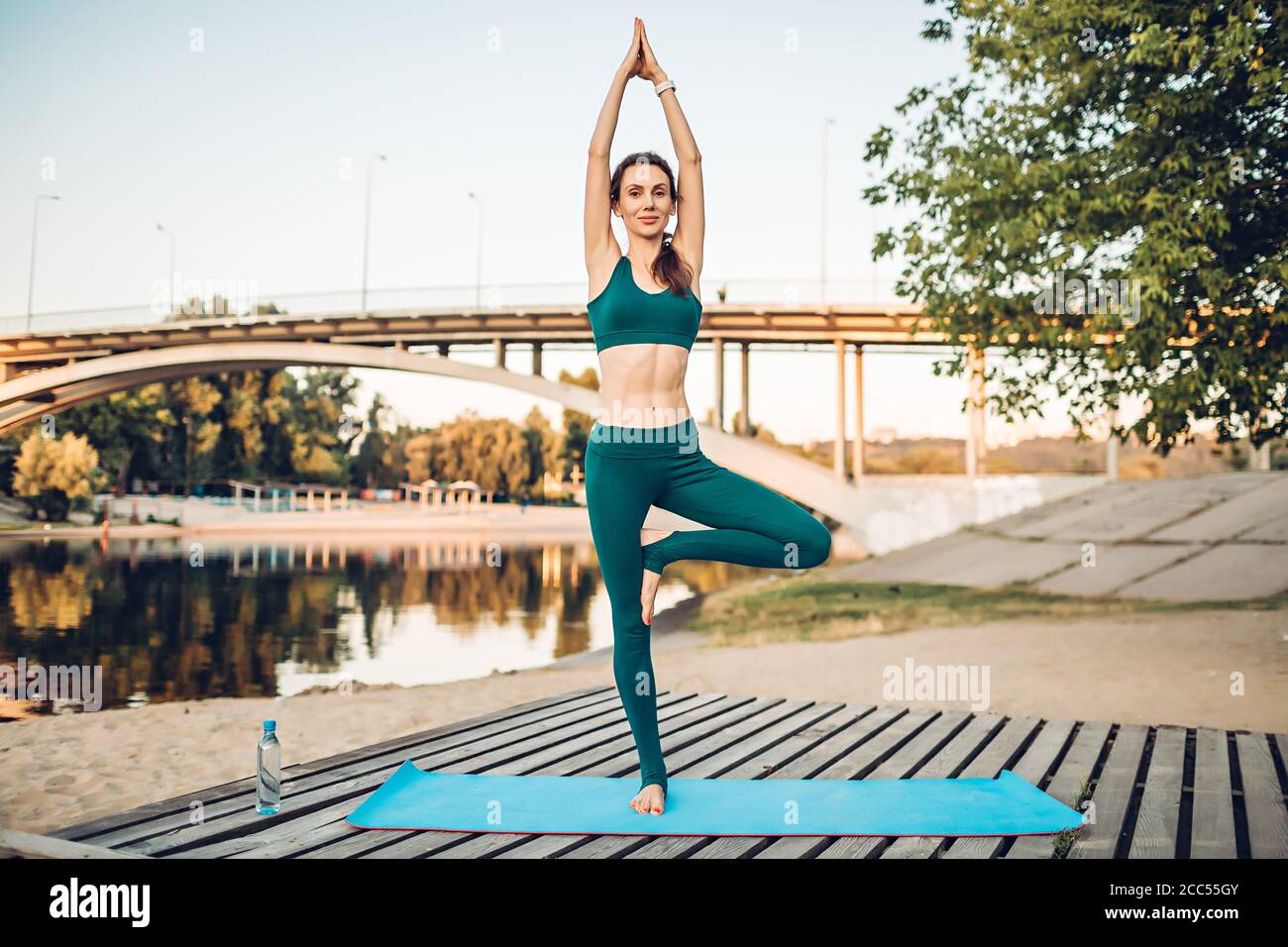 Sport donna fare yoga su piattaforma di legno Foto Stock