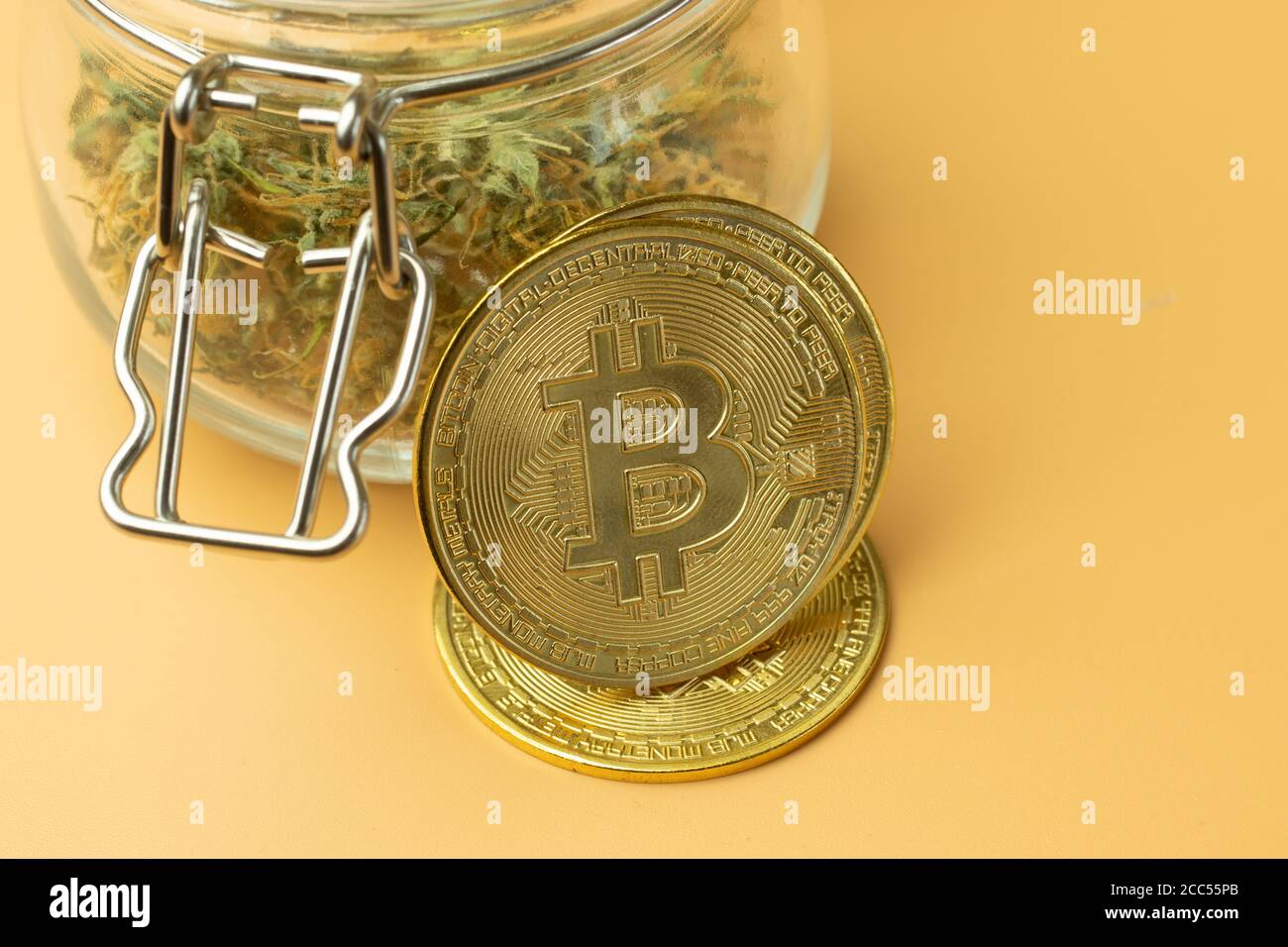 Bitcoin criptovaluta uso nell'acquisto di farmaci in forma anonima. Acquisto di marijuana per moneta btc. Primo piano su sfondo arancione Foto Stock
