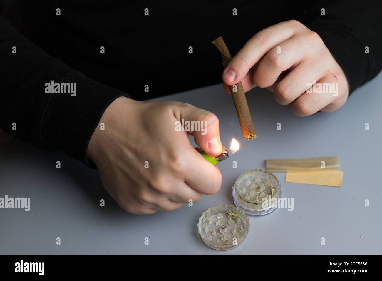 L'uomo illumina la marijuana smussata, il processo di fumo di cannabis, l'uso di erbacce Foto Stock