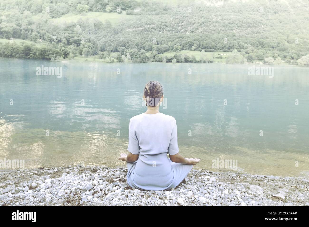 donna che fa yoga di fronte ad uno spettacolare lago di montagna Foto Stock