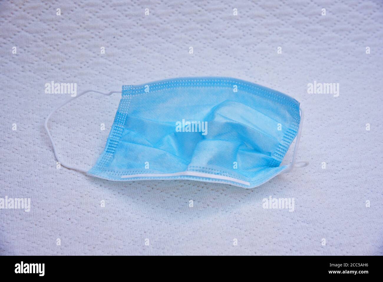 Maschera chirurgica monouso su tessuto bianco sfondo Foto Stock