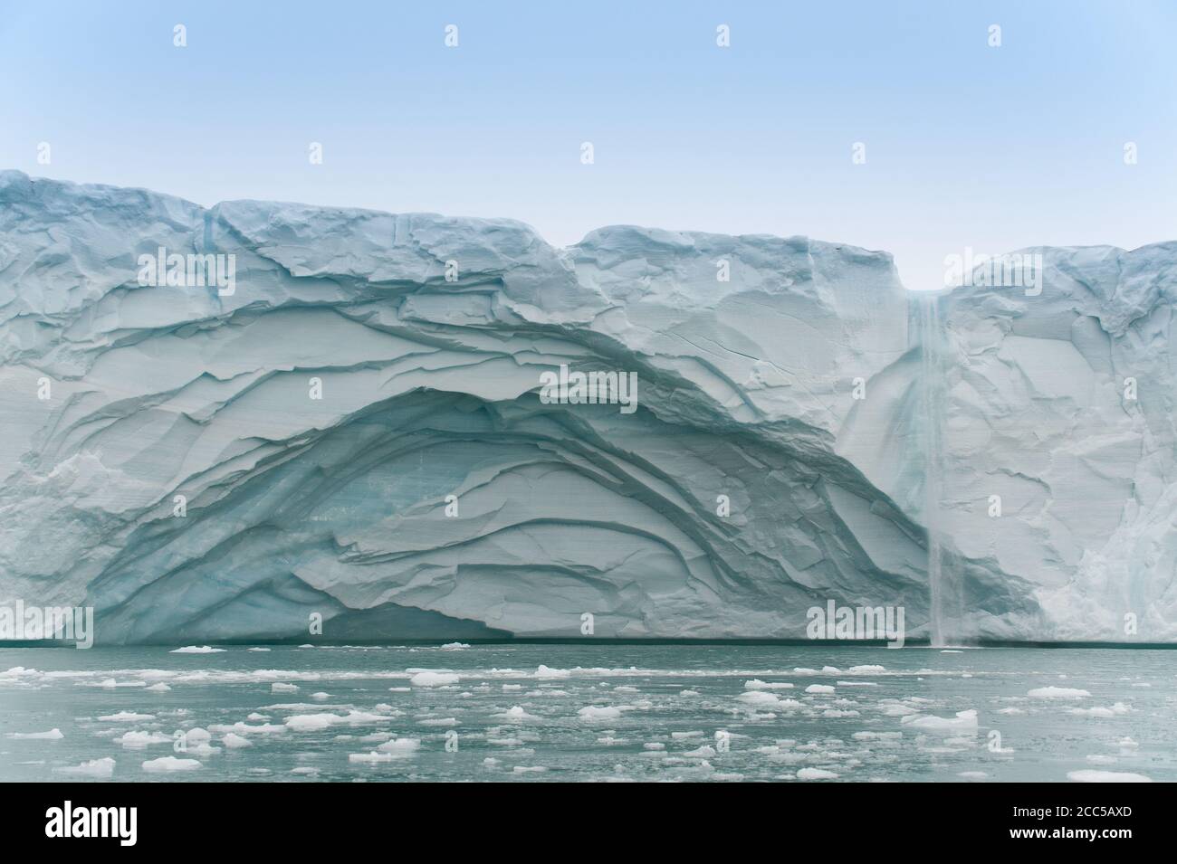 Vista dal mare una parete glaciale ha recentemente calato e. Collapsed, frammenti di ghiaccio galleggiano in foreground.Melting ghiaccio ha formato una cascata che cascata Foto Stock