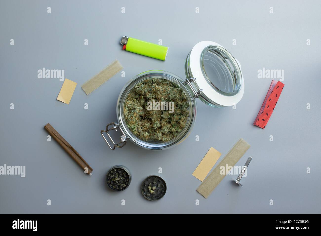 Vista dall'alto del fumo di cannabis. Marijuana e carta su sfondo grigio Foto Stock