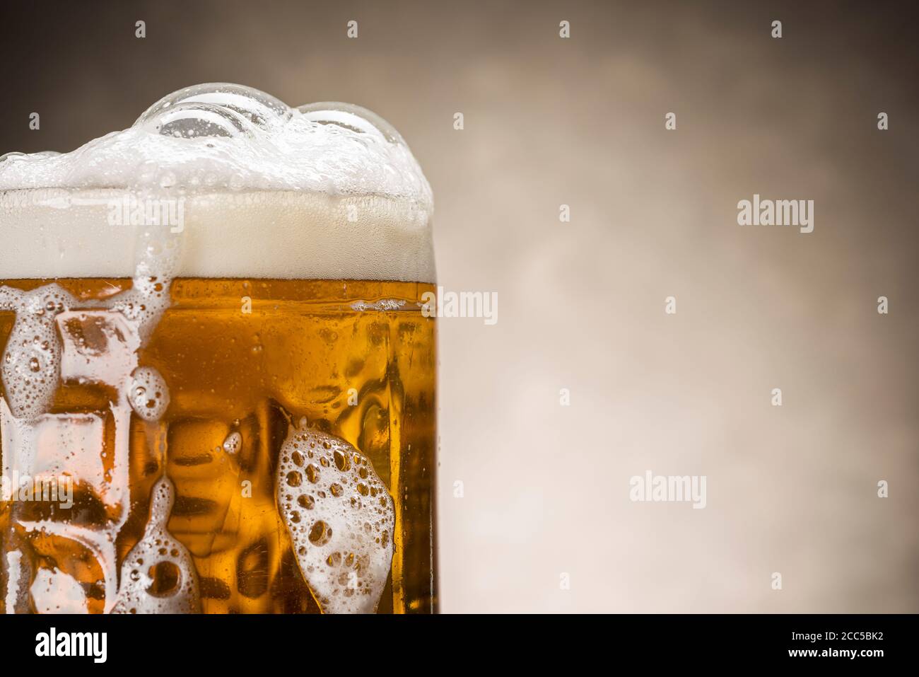 primo piano di pinta di birra con schiuma su sfondo rustico Foto Stock