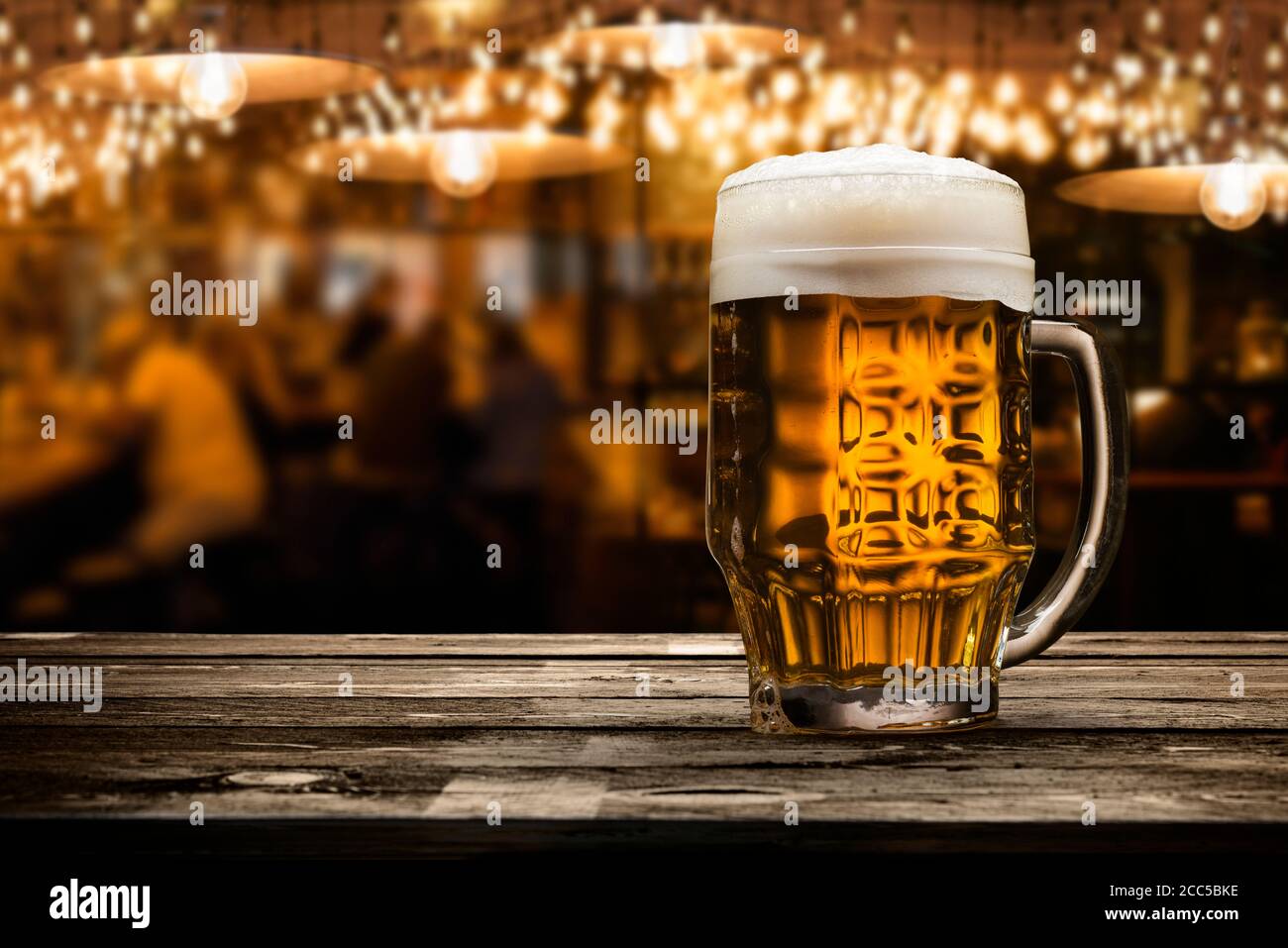 pinta di birra bionda con schiuma su tavolo di legno all'interno un pub Foto Stock